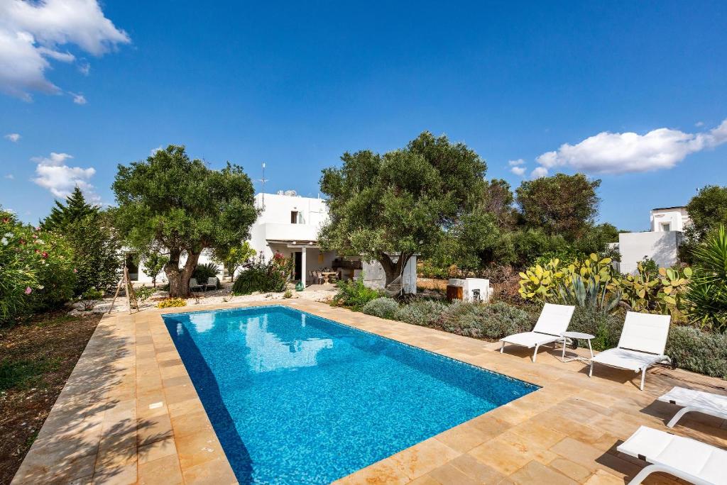 a swimming pool with two chairs and a house at Casale La Stella by Perle di Puglia in San Michele Salentino