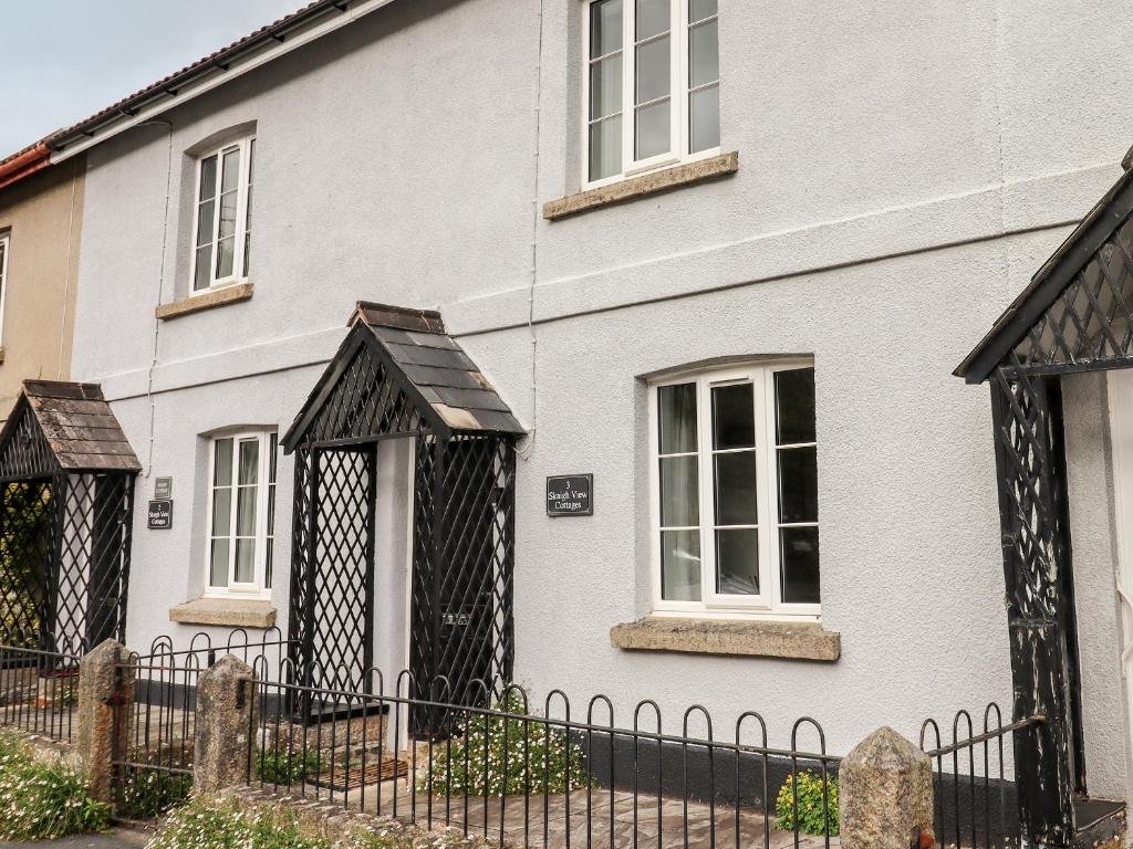 a white house with a black fence at 3 Skaigh View Cottages in Okehampton