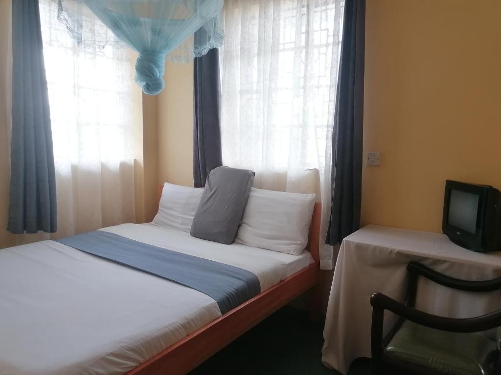 een slaapkamer met een bed, een tv en een raam bij Forest green Inn in Kakamega