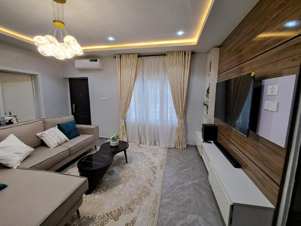 ein Wohnzimmer mit einem Sofa und einem Flachbild-TV in der Unterkunft The Palladium Apartments in Ebute Lekki