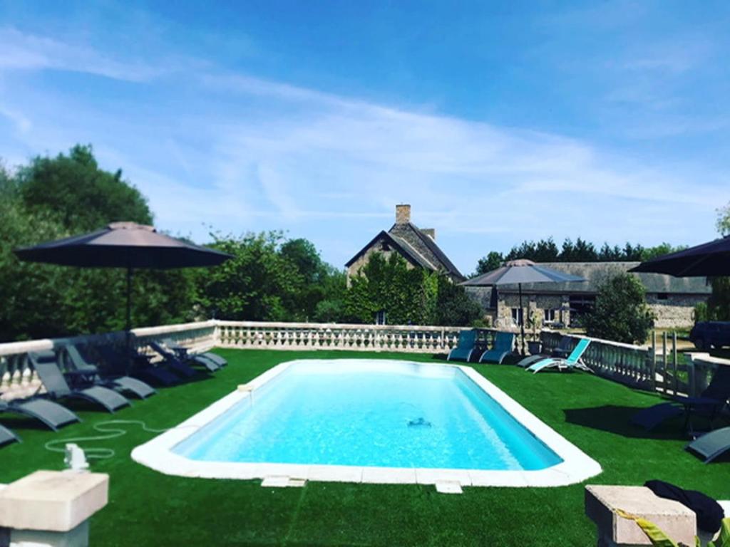 een groot zwembad met stoelen en een parasol bij Bayeux - Domaine Le Vivier in Castillon