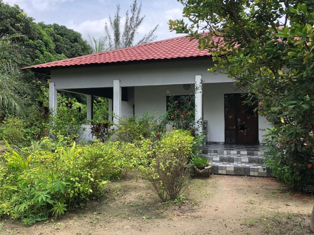 una pequeña casa blanca con techo rojo en Karamaluu Garden Lodge, en Gunjur