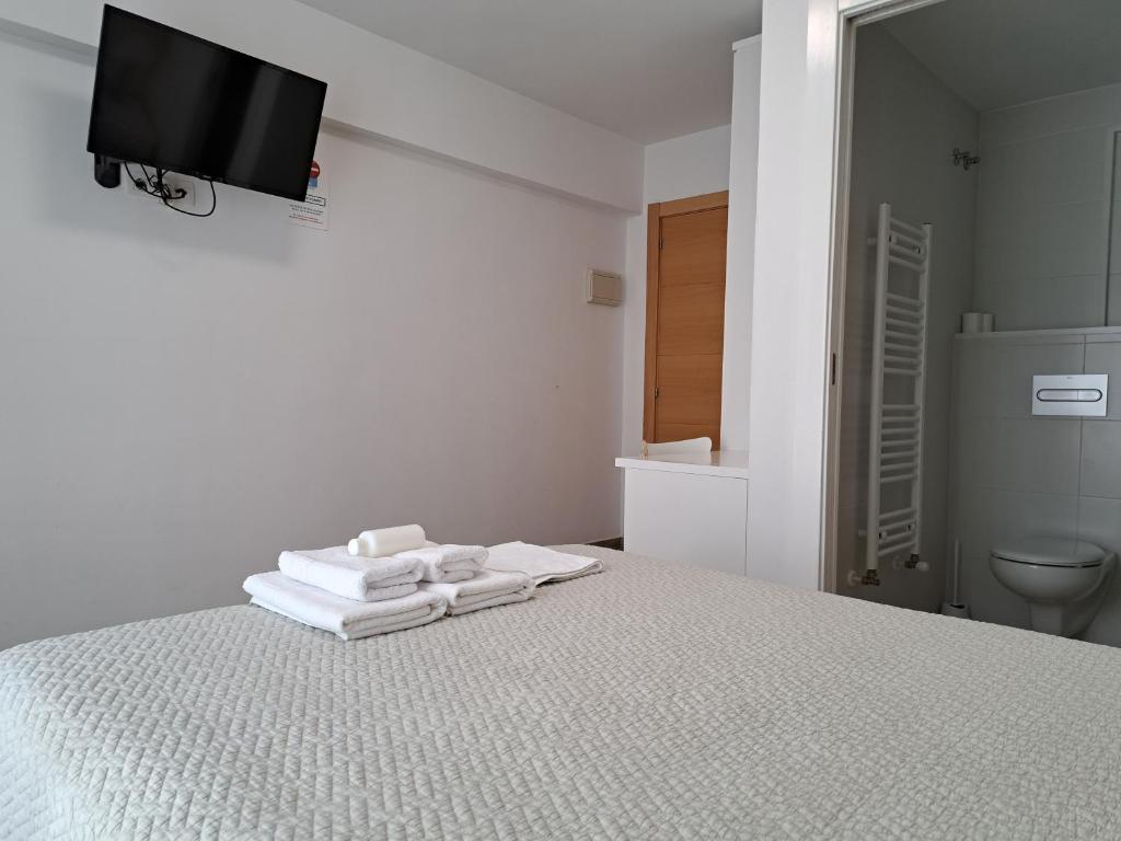 a white bedroom with a bed with towels on it at Pension Iruna in Santurce