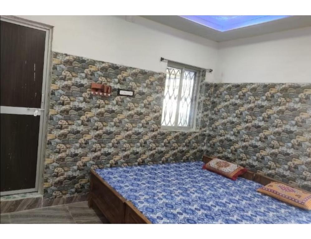 1 dormitorio con 1 cama en una pared de piedra en Eeshwar Lodge, Patnagarh, Odisha 