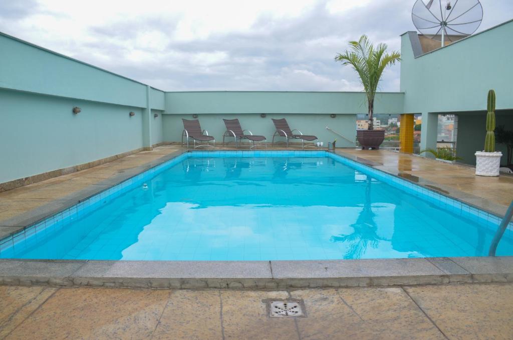 a swimming pool with blue water in a building at Riviera Palace Hotel in Sete Lagoas