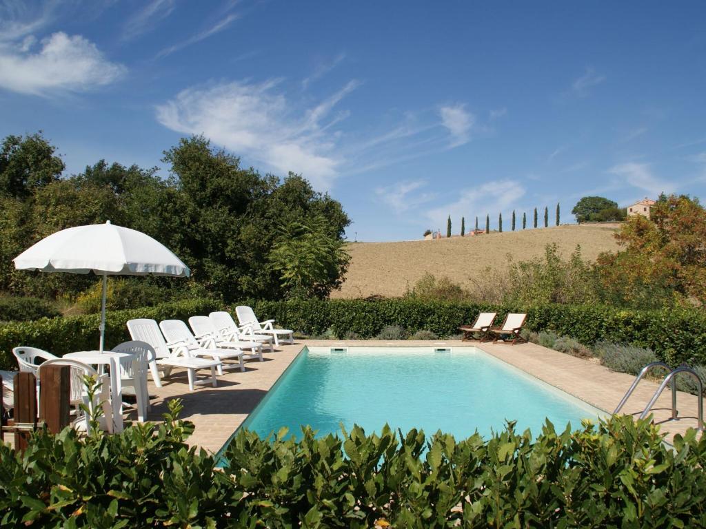 uma piscina com cadeiras brancas e um guarda-sol em Charming holiday home in Treia with shared pool em Avenale