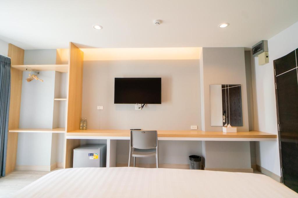 a bedroom with a bed and a desk with a tv at Goodday Hotel in Ban Nong Waeng