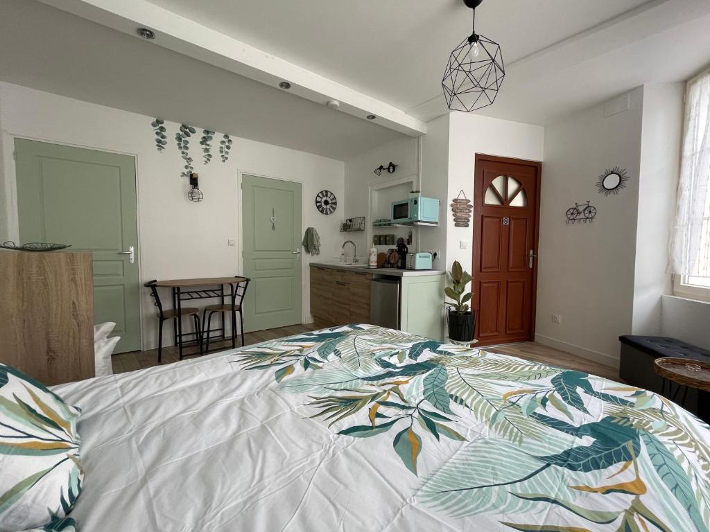 a bedroom with a large bed and a kitchen at Studio de la Poterie in Vermenton