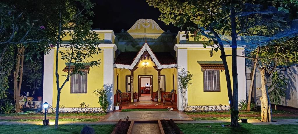 a yellow house with a front door at night at xplorest in Mysore
