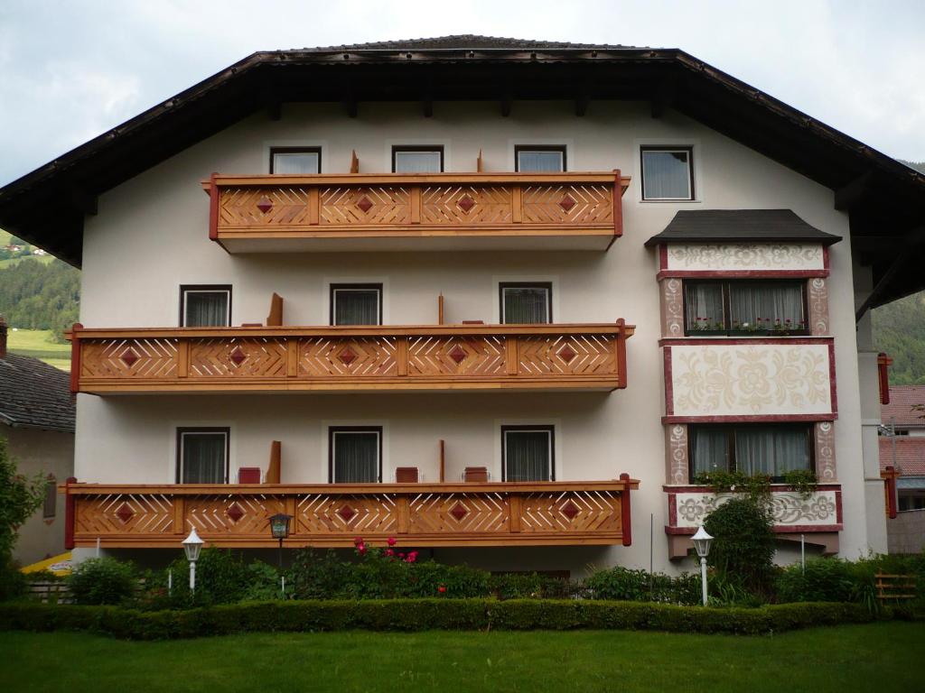 un grande edificio bianco con balcone in legno di Hotel Alpenrose a Rodengo