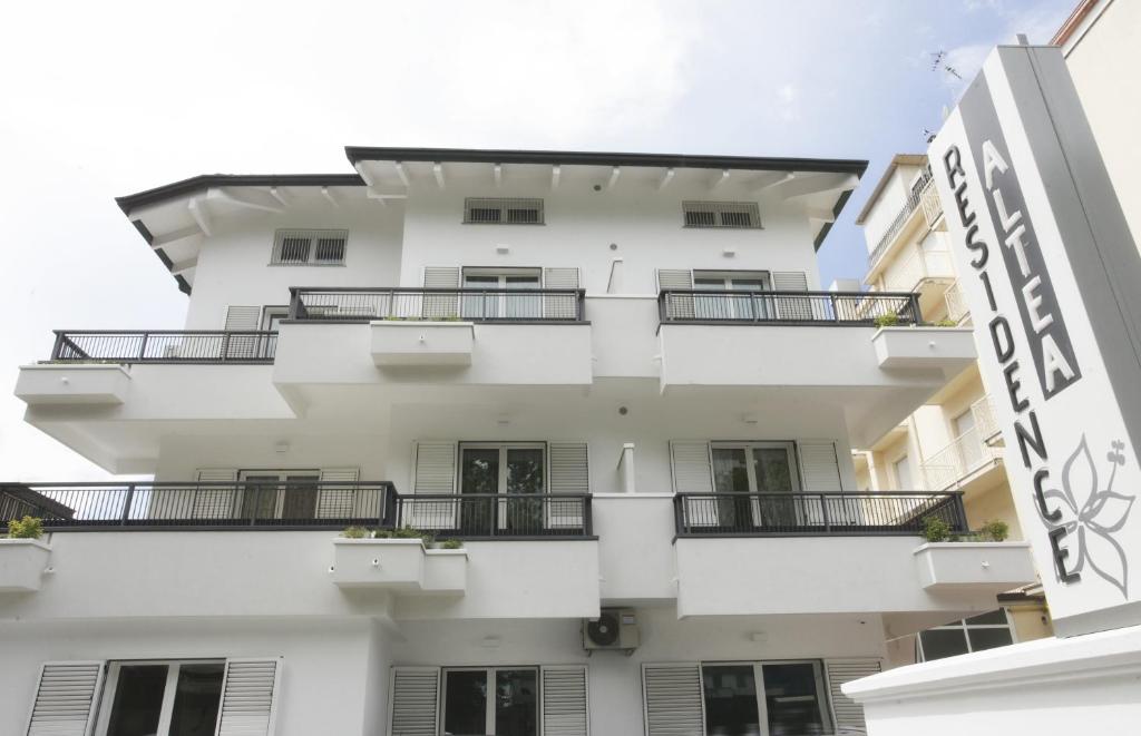 a white building with balconies and a sign at Residence Altea in Riccione