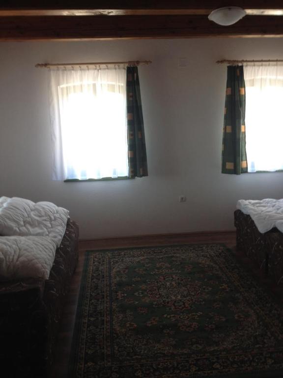 a bedroom with two beds and a window and a rug at Jázmin Vendégház in Homokbödöge