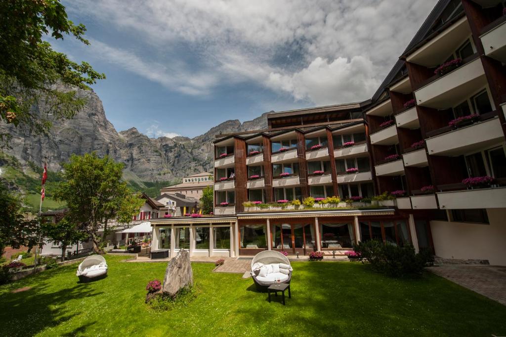 a hotel with a green lawn in front of a mountain at Quellenhof UNIQUE in Leukerbad