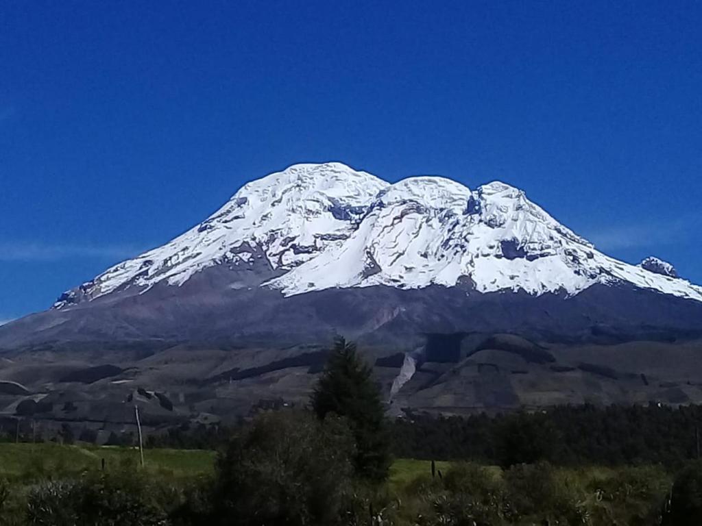 una montaña cubierta de nieve en un cielo azul claro en CASA IDEAL en Riobamba