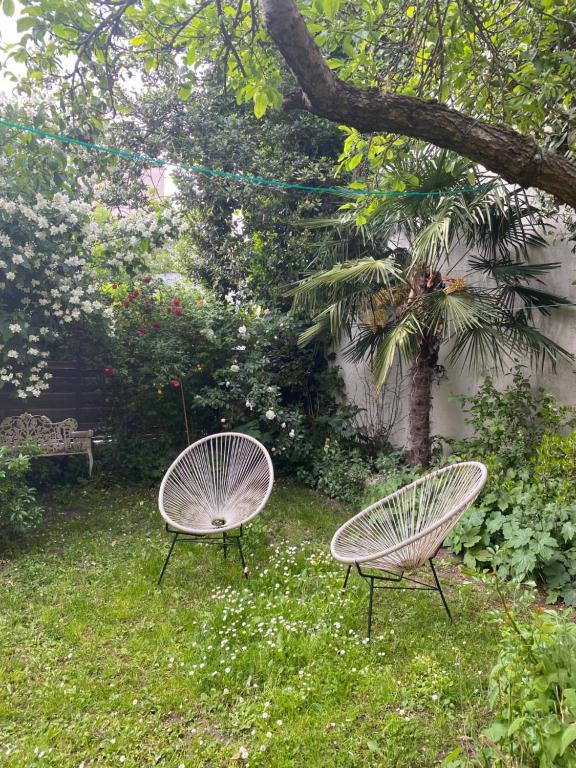 two chairs sitting in the grass in a yard at Maison piscine centre historique de Romainville in Romainville