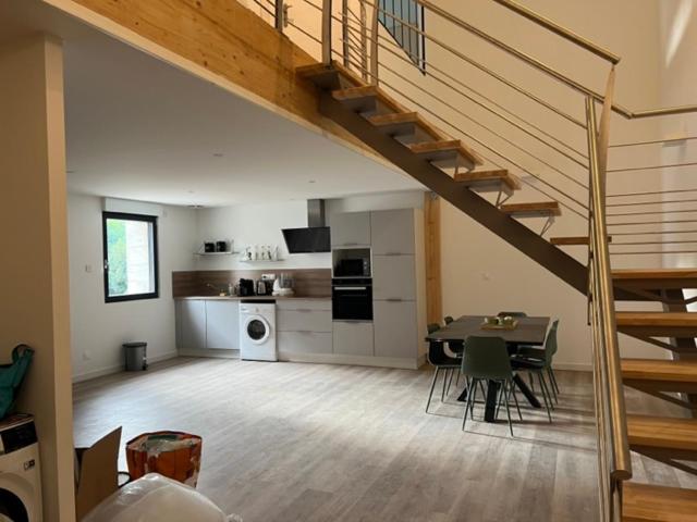 Il comprend un salon avec une table et une cuisine avec un escalier. dans l'établissement Le Vox - appartement de centre-ville, à Montélimar