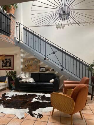 a living room with a couch and a staircase at Maison piscine centre historique de Romainville in Romainville