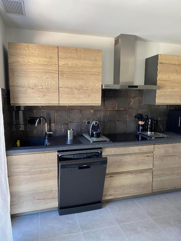 - une cuisine avec des placards en bois et un lave-vaisselle noir dans l'établissement Appartements 300 mètres de la mer et villa, à Saint-Florent