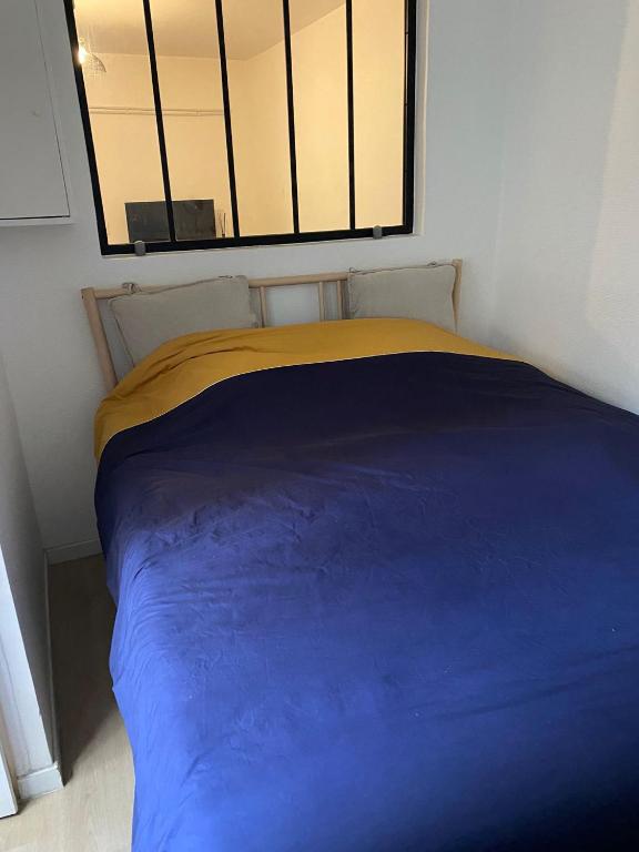 - un lit bleu dans une chambre avec fenêtre dans l'établissement Au pied du Sacré Cœur, à Paris