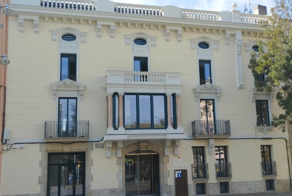 un gran edificio blanco con ventanas y balcones en Cal Maco Alberg i centre de visitants en Igualada