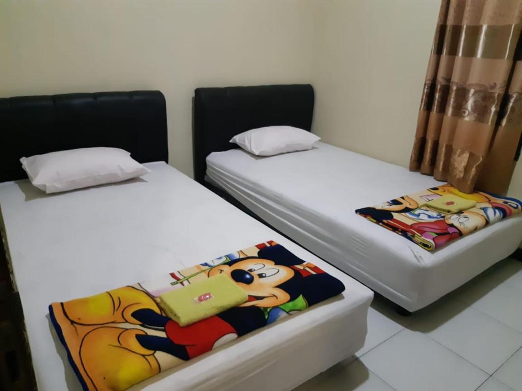 Duas camas individuais sentadas uma ao lado da outra num quarto em King Plaza Homestay em Tanjungredep