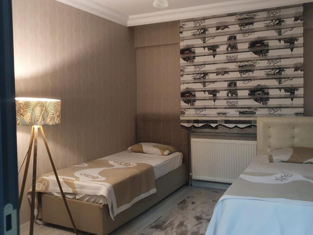 a small bedroom with two beds and a lamp at Mükemmel Konum'da Lüx Dairede Konaklama in Sivas