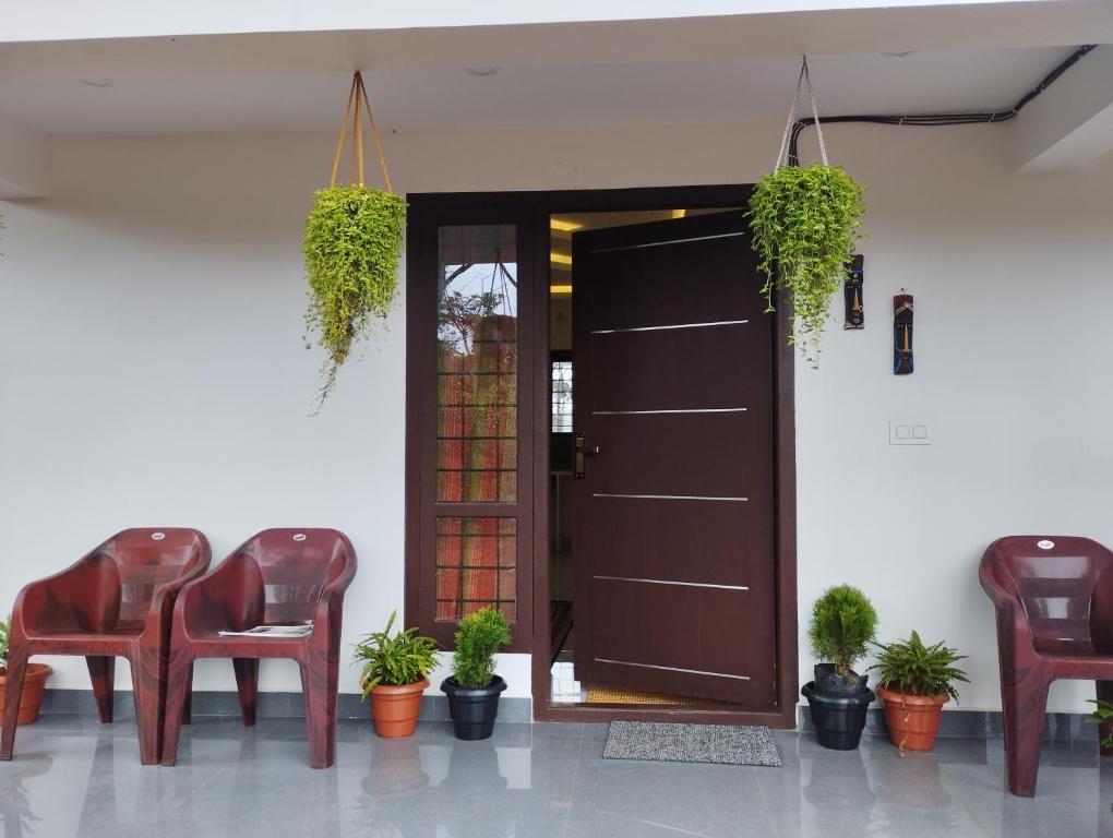 een kamer met stoelen en een deur met planten bij SHI's Vagamon Hill Retreat- Private villa on Hills in Vagamon