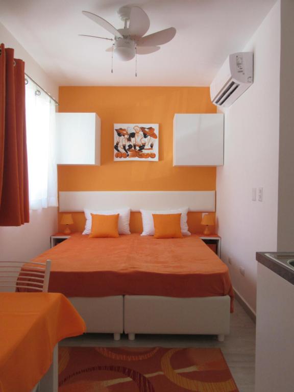 Schlafzimmer mit einem Bett mit einem orangefarbenen Kopfteil in der Unterkunft SEVEN SHADES OF CORAL VILLAGE - suites & pool in a residence close to the beach in Punta Cana