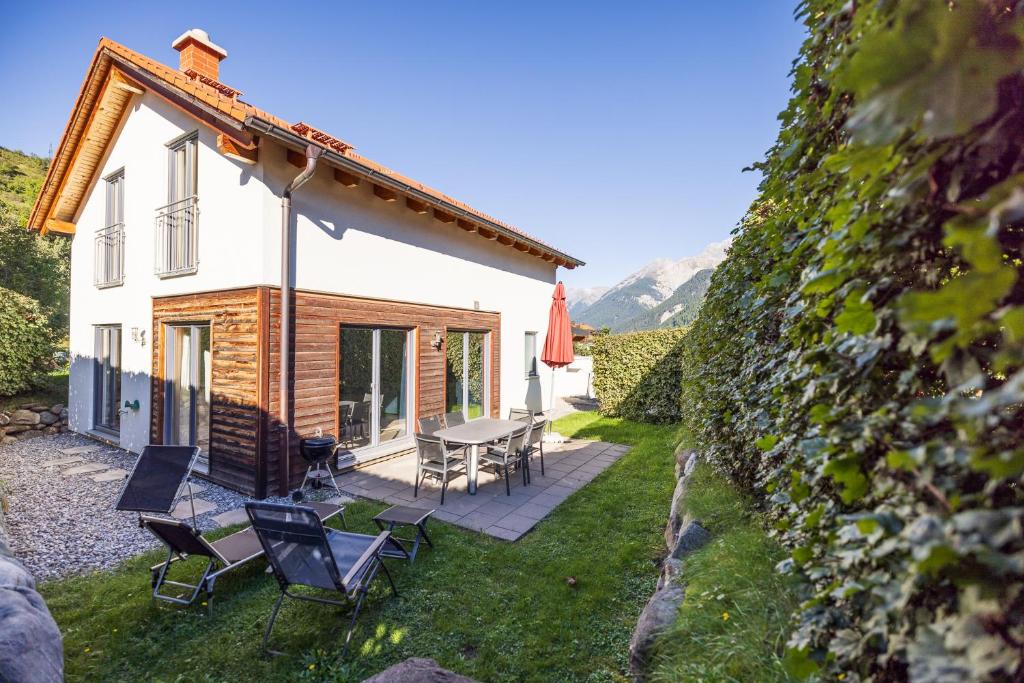 ein kleines Haus mit einer Terrasse, einem Tisch und Stühlen in der Unterkunft Pütvia 245F in Scuol