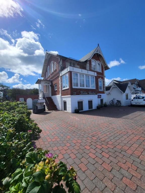 ein großes Haus mit einer Ziegelsteinfahrt in der Unterkunft Villa Wally in Westerland