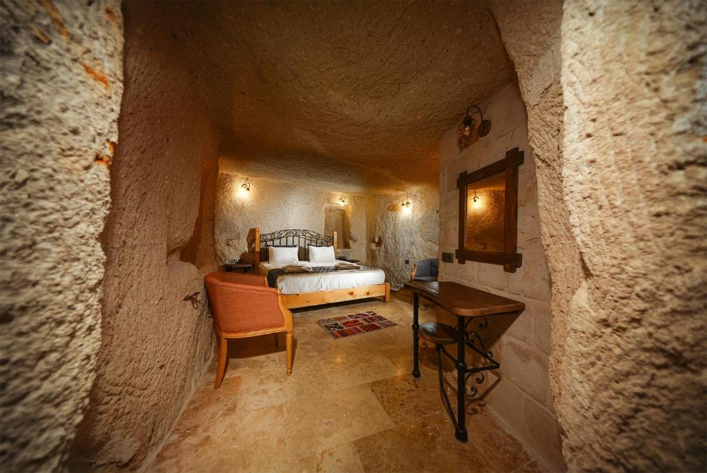 een slaapkamer met een bed en een tafel in een grot bij Caverna Hotel Premium Caves in Goreme