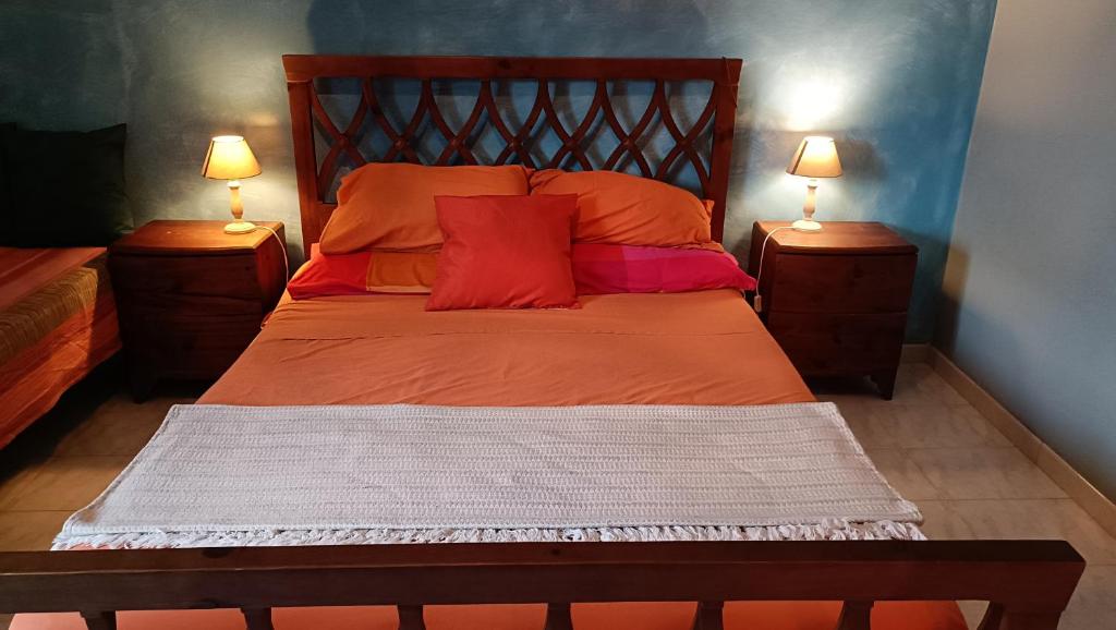 a bedroom with a bed with orange sheets and two lamps at Casa con Giardino in Milazzo