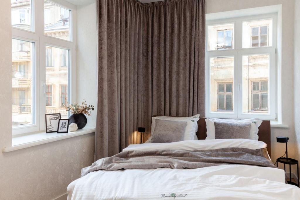 two beds in a bedroom with two windows at Romari Vip Дорошенка 13 in Lviv