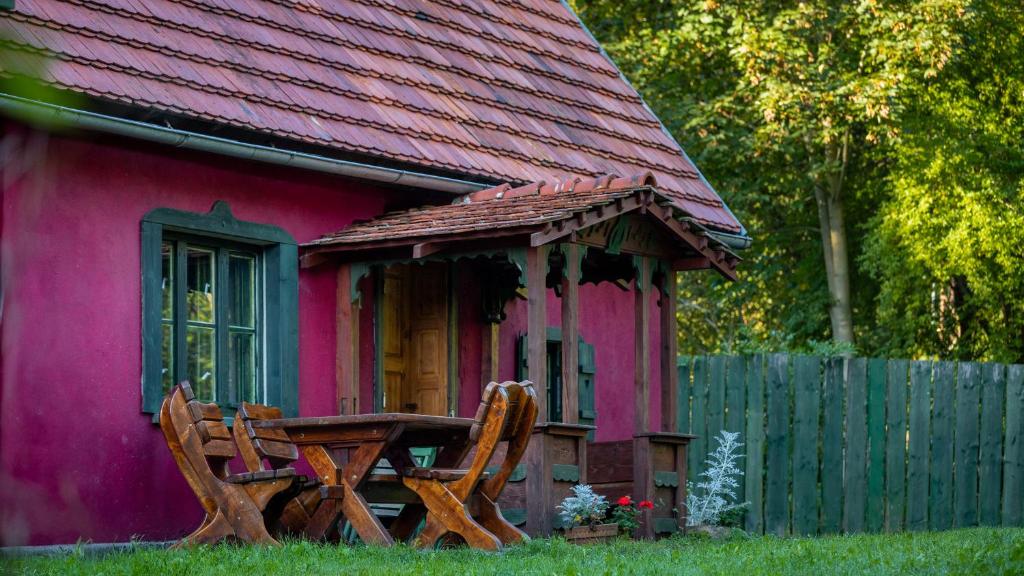 Una casa rosa con una mesa y un banco delante de ella. en Apartamenty EverySky Janice, en Grudza
