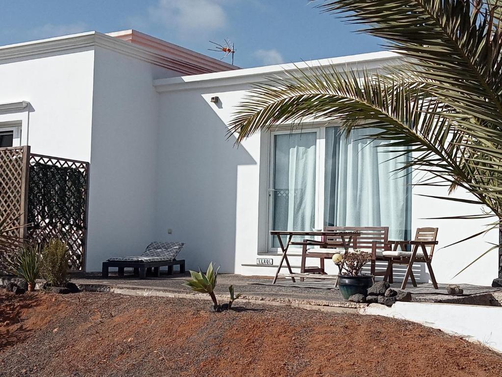 a white house with a table and a bench at Quintero Suites in San Bartolomé