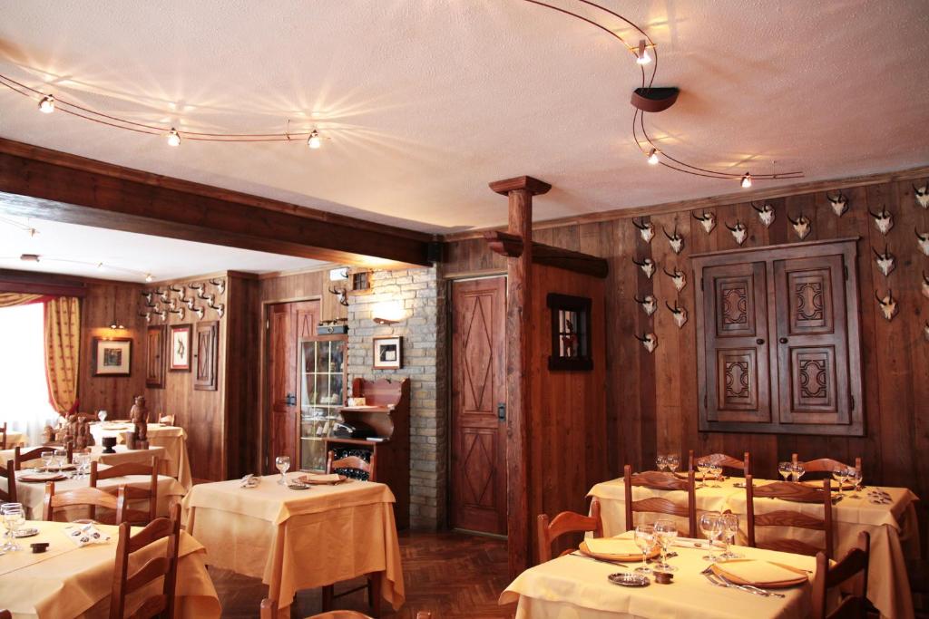 a dining room with tables with white tablecloths at Hotel Dei Camosci in Courmayeur