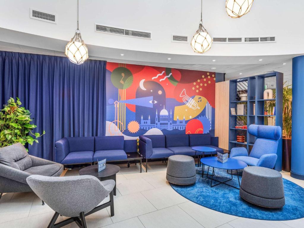 ein Wartezimmer mit blauen Sofas und einem Wandbild in der Unterkunft Ibis Budapest Centrum in Budapest