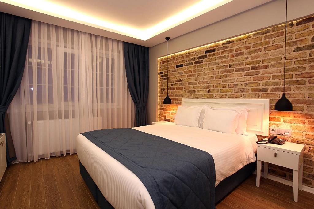 a bedroom with a large bed and a brick wall at Taksim Santa Lucia Hotel in Istanbul