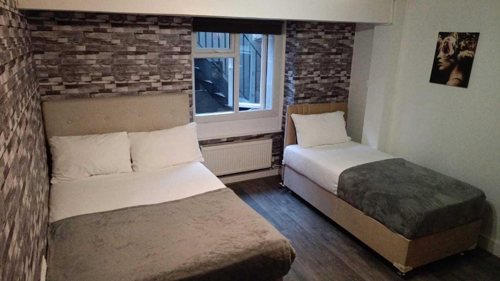 a bedroom with two beds and a window at Comfortable Budget Two Bedroom Apartment In City Centre - Kings Cross - Euston Station - 6 People in London