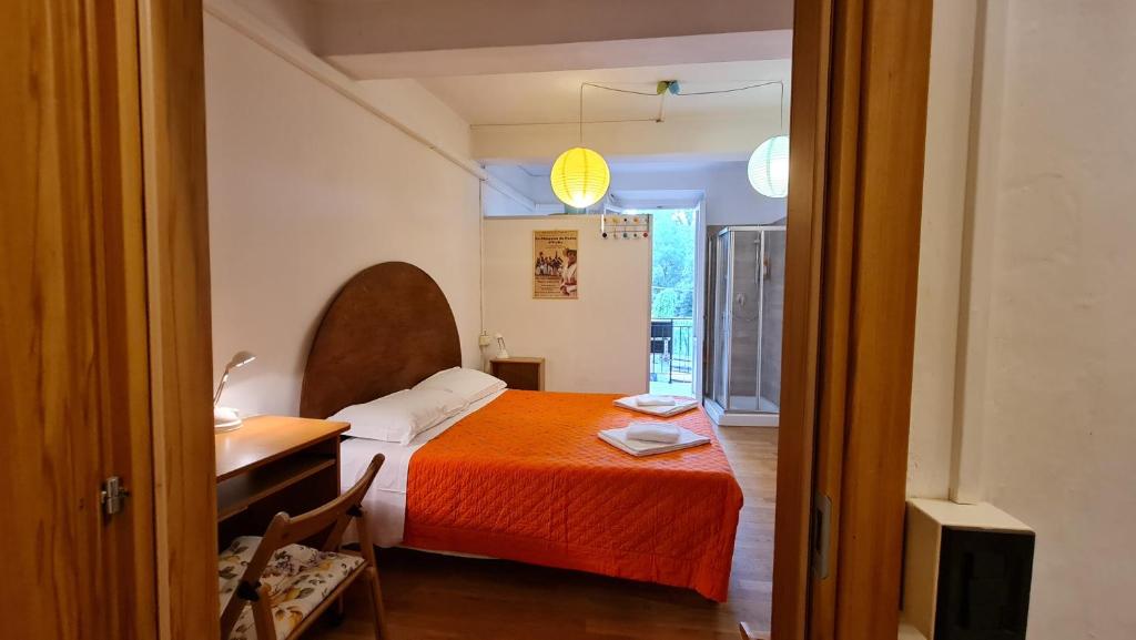 ein Schlafzimmer mit einem Bett mit einer orangefarbenen Decke und einem Schreibtisch in der Unterkunft Giulio in Santo Spirito in Florenz