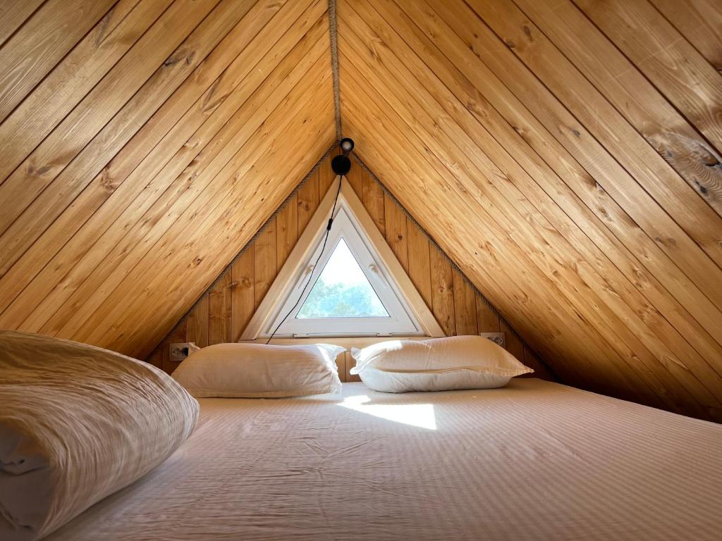 a bed in a wooden room with a window at Bereke Kolsay Resort in Saty