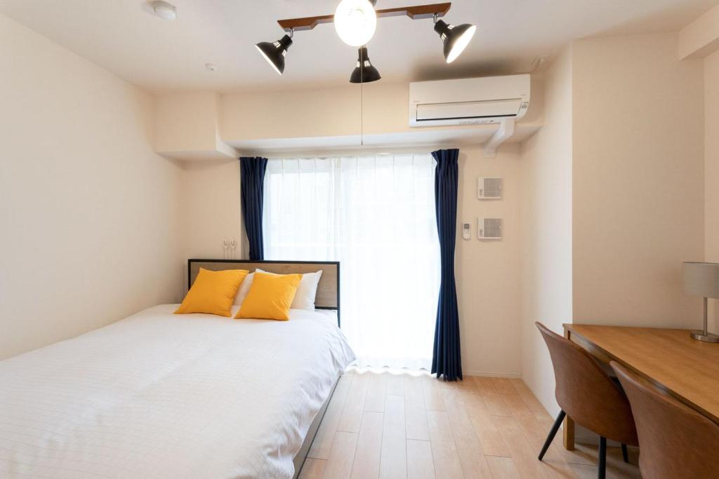 a bedroom with a bed and a desk and a window at Crest Court Kagurazaka in Tokyo