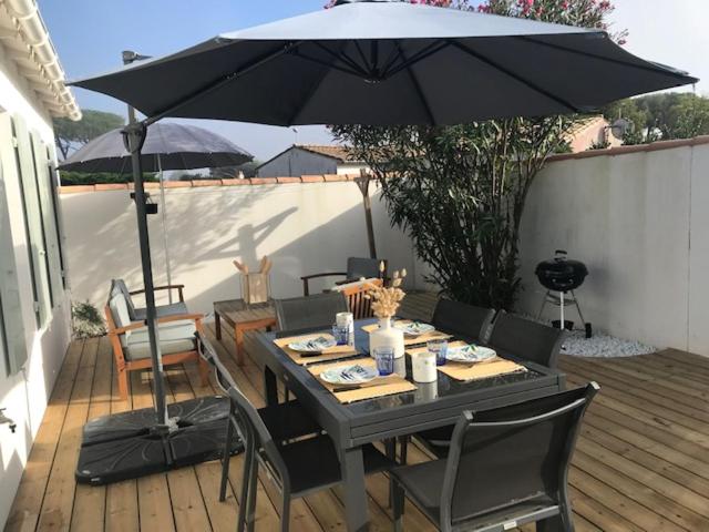 - une table avec un parasol sur une terrasse en bois dans l'établissement AGAPANTHES Jolie Maison proche Plage et Commerces, au Bois-Plage-en-Ré