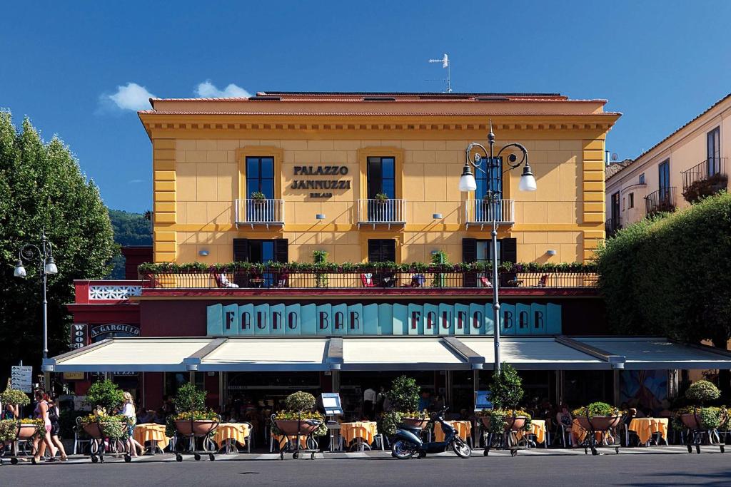 ein großes Gebäude mit Tischen und Stühlen davor in der Unterkunft Palazzo Jannuzzi Relais in Sorrent