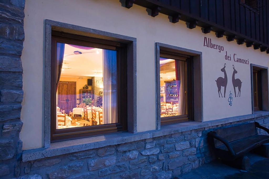 a building with three windows with a bench in front at Hotel Dei Camosci in Courmayeur