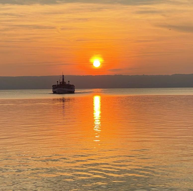 a boat on the water at sunset at Panoramahaus am Ammersee I Sauna I Wellness I Kamin in Herrsching am Ammersee