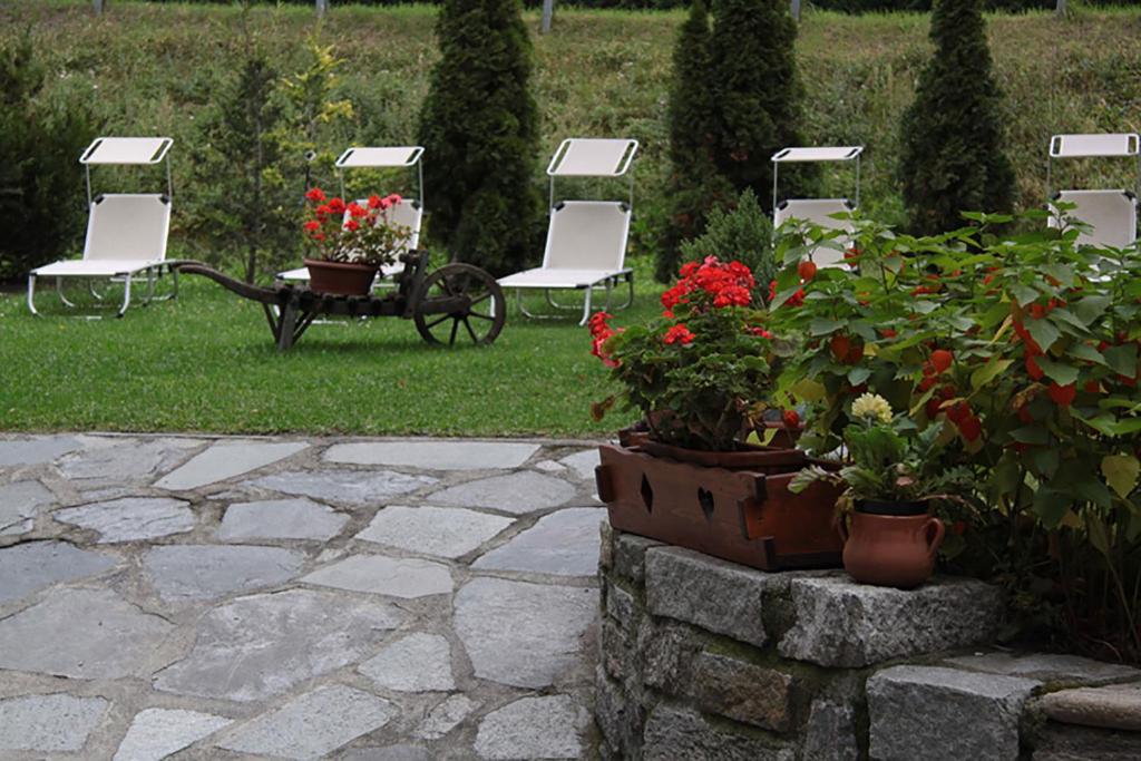 a patio with chairs and flowers and a table and chairs at Hotel Dei Camosci in Courmayeur