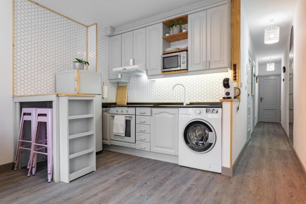 a kitchen with white cabinets and a washing machine at Peixe Frito Apartment in Pontevedra