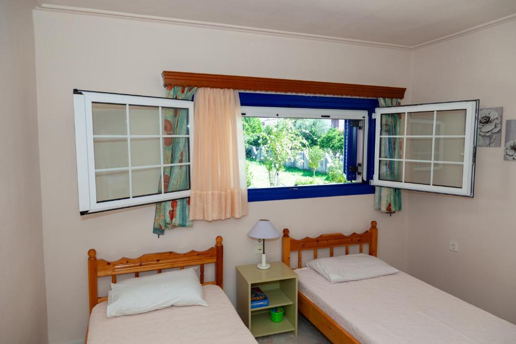 two beds in a room with two windows at Liakos' Apartments in Vasiliká