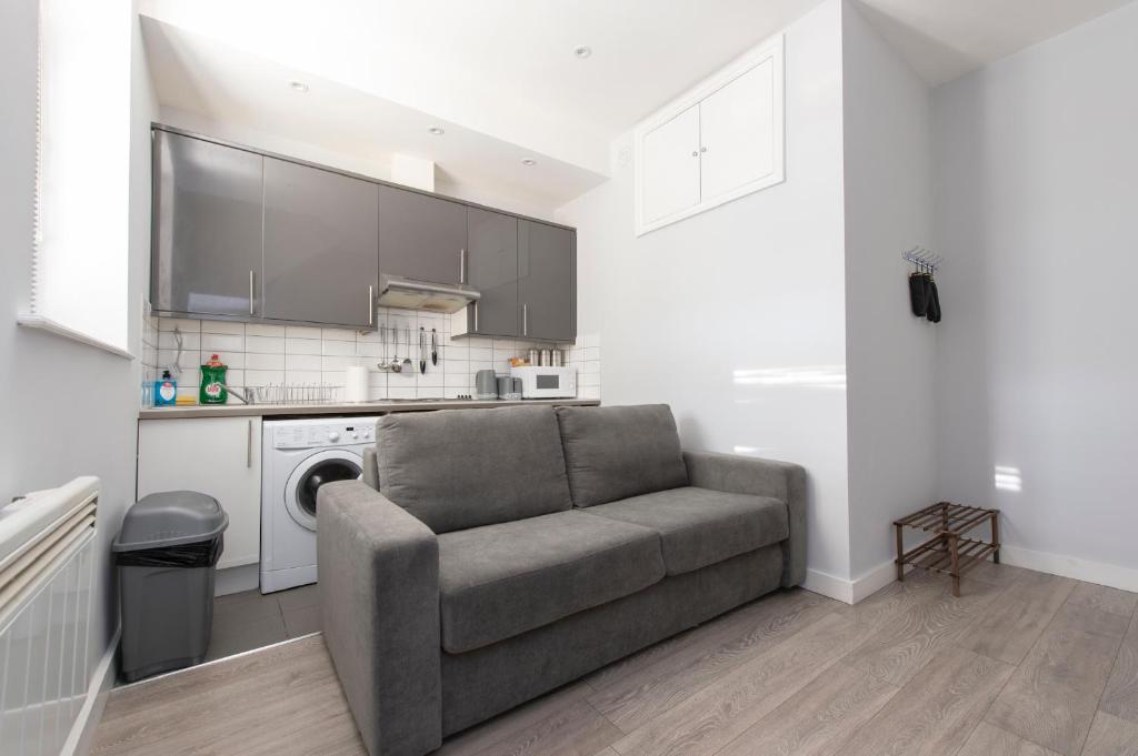 a living room with a couch and a kitchen at Fab garden flat central Camden in London